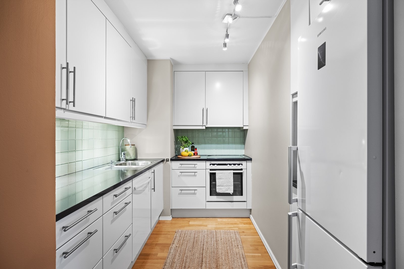 Norema kjøkkeninnredning med glatte fronter, benkeplate i granitt og fliser på vegg over benkeskap Galleribilde