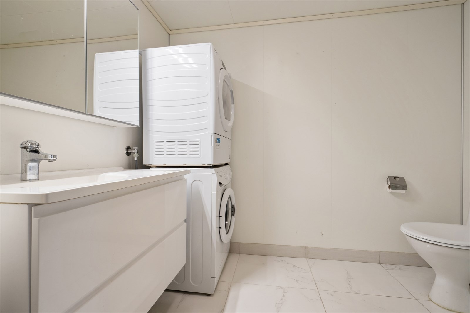 Leiligheten har et funksjonelt kombinert bad og vaskerom, hvor gulvet er oppgradert med flis lagt over vinyl. Elektriske varmekabler sørger for lun komfort gjennom året. Galleribilde