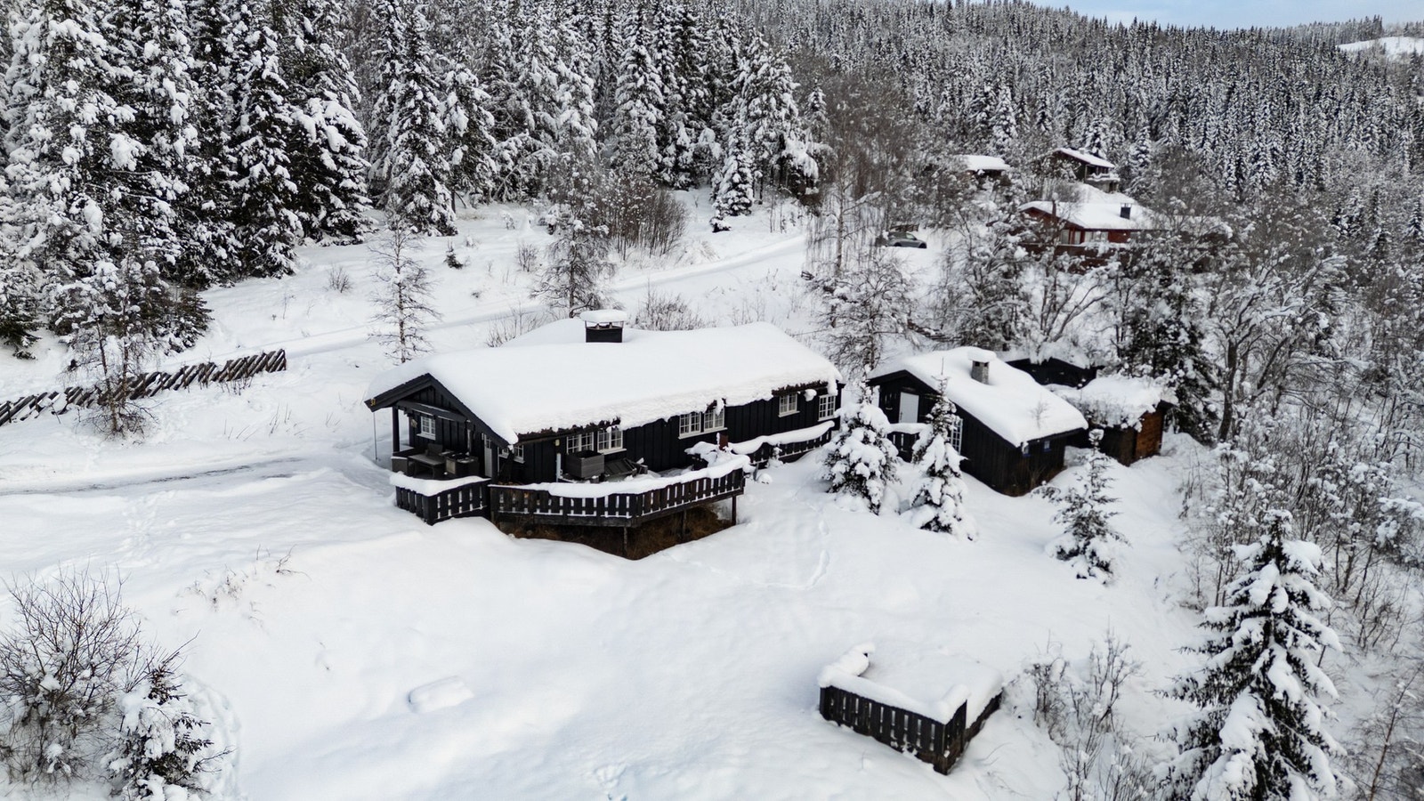 Romslig veranda som går rundt store deler av hytte med med flere soner for utemøblering gjør det enkelt og innbydende å nyte utsikten og de gode solforholdene utendørs. Galleribilde