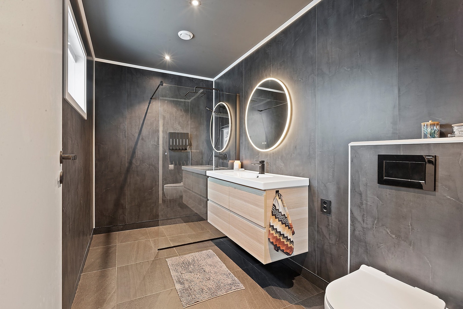 Badet i 2. etasje er tidsriktig og moderne, med innredning som inkluderer nedfelt servant med skuffer under, speil med integrert belysning, dusjhjørne og vegghengt toalett. I tillegg har badet varme i gulvet. Galleribilde