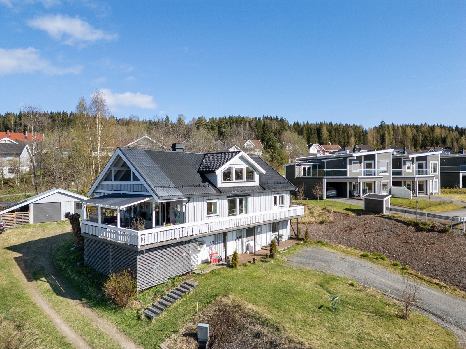 Boligen ligger fint til i terrenget og er omkranset av plener på to plan Galleribilde