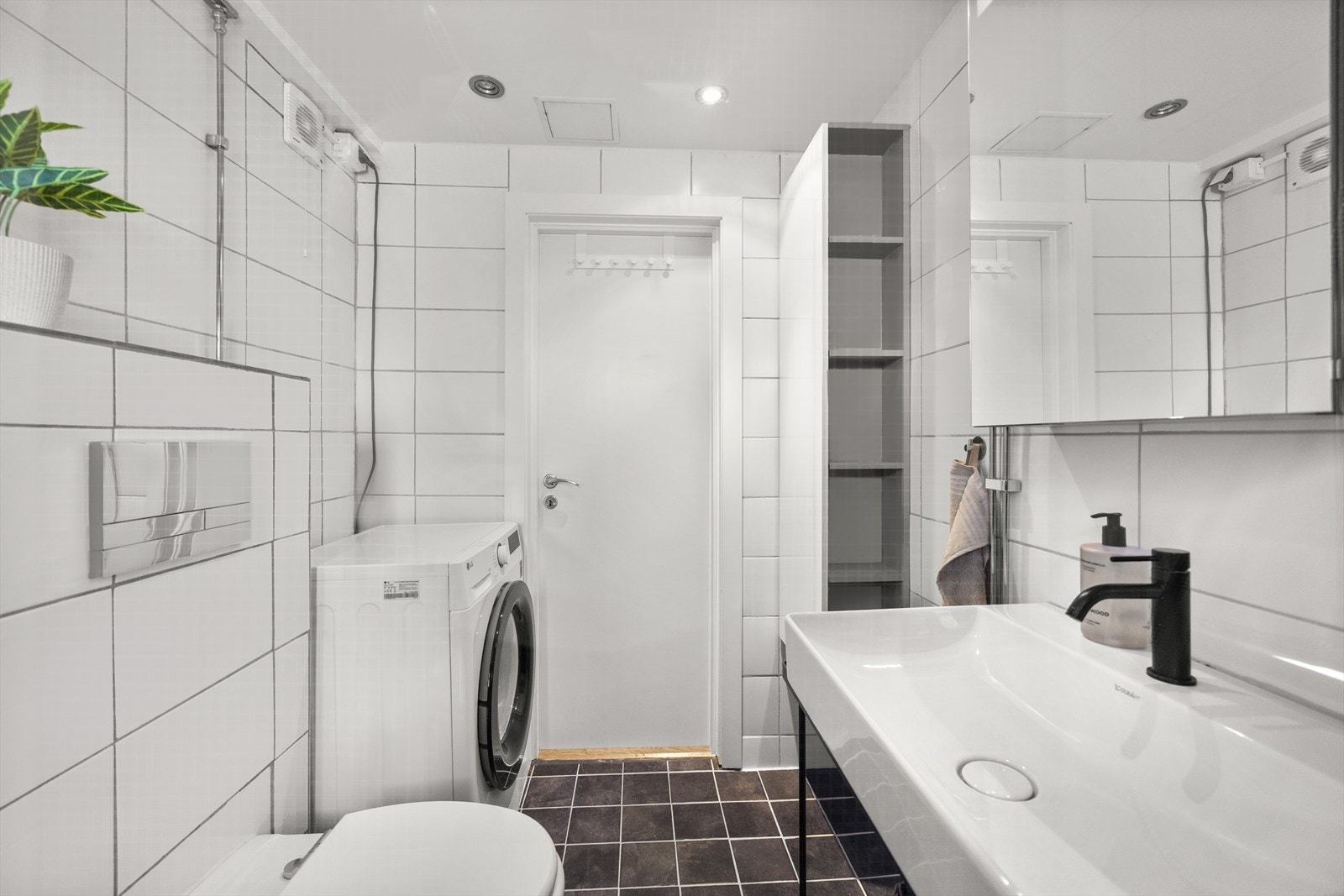 Rommet er innredet med en vegghengt toalett med innebygget sisterne, et avskjermet dusjhjørne med glassvegger og dobbel dusj, samt en servant med åpen hylle under. Galleribilde