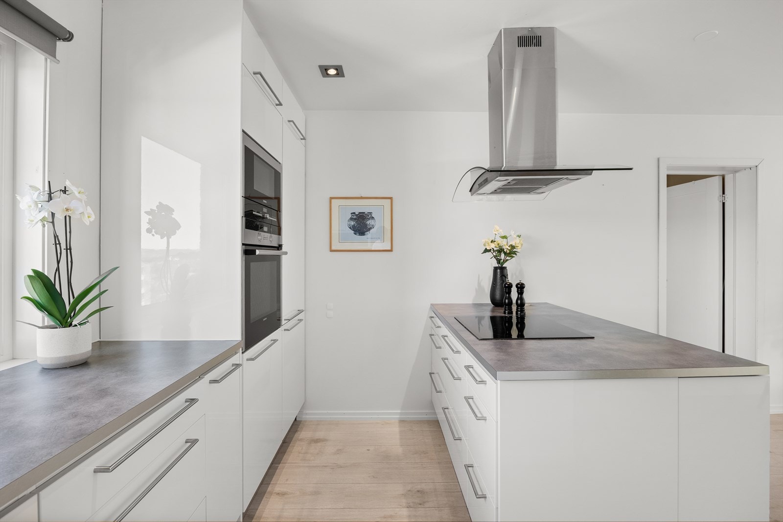 Praktisk kjøkkenøy med integrert koketopp og ventilator skaper en funksjonell og sosial arbeidsflate. Galleribilde