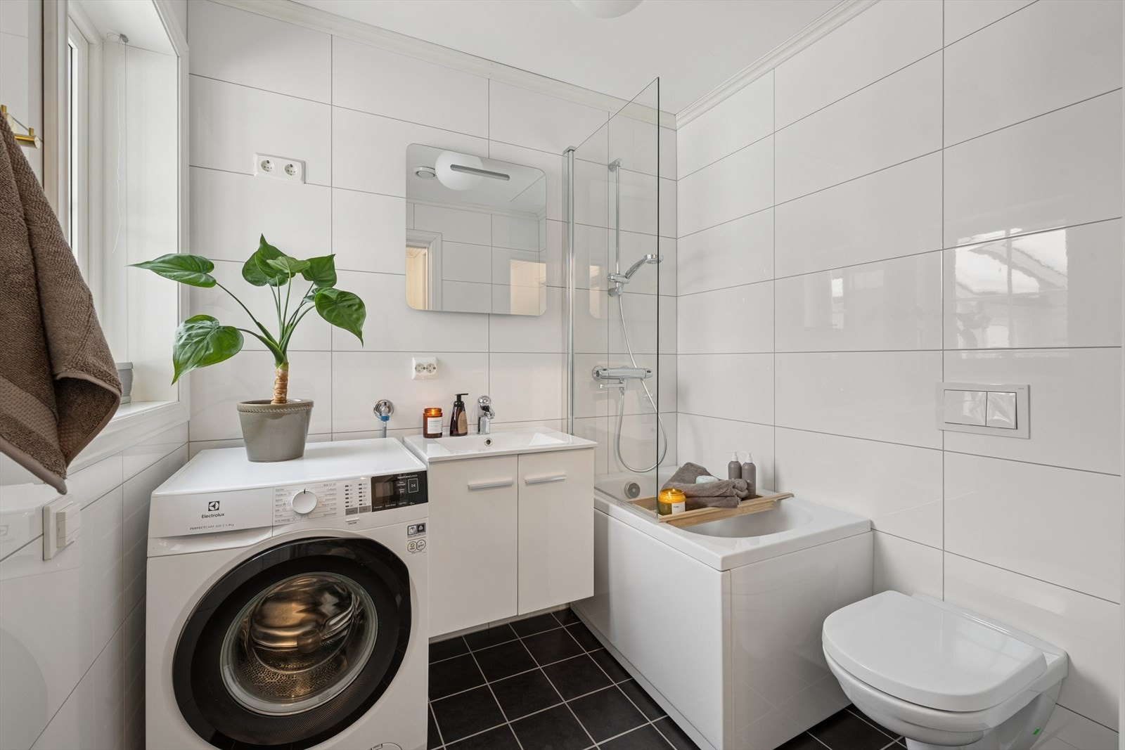 Flislagt bad i 1.etg. med veggmontert toalett, servant med innredning, badekar, opplegg for vaskemaskin og gulvvarme. Galleribilde