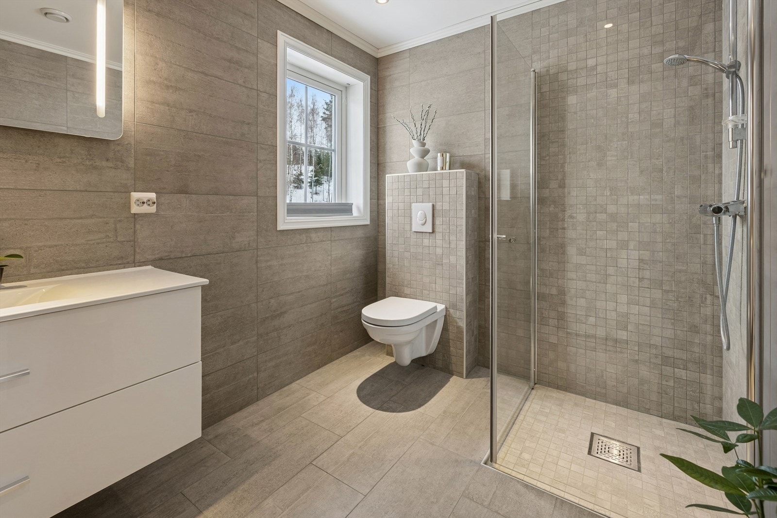 Flislagt bad i 2.etg. med veggmontert toalett, servant med innredning, dusjvegger/hjørne og gulvvarme. Galleribilde