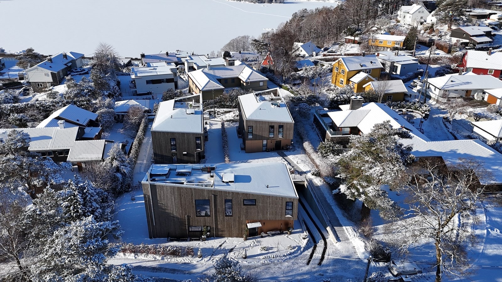 Boligen ligger til venstre blant disse 3 funkishusene fra 2023. Nedkjørsel ti felles garasjeanlegg til høyre. Galleribilde