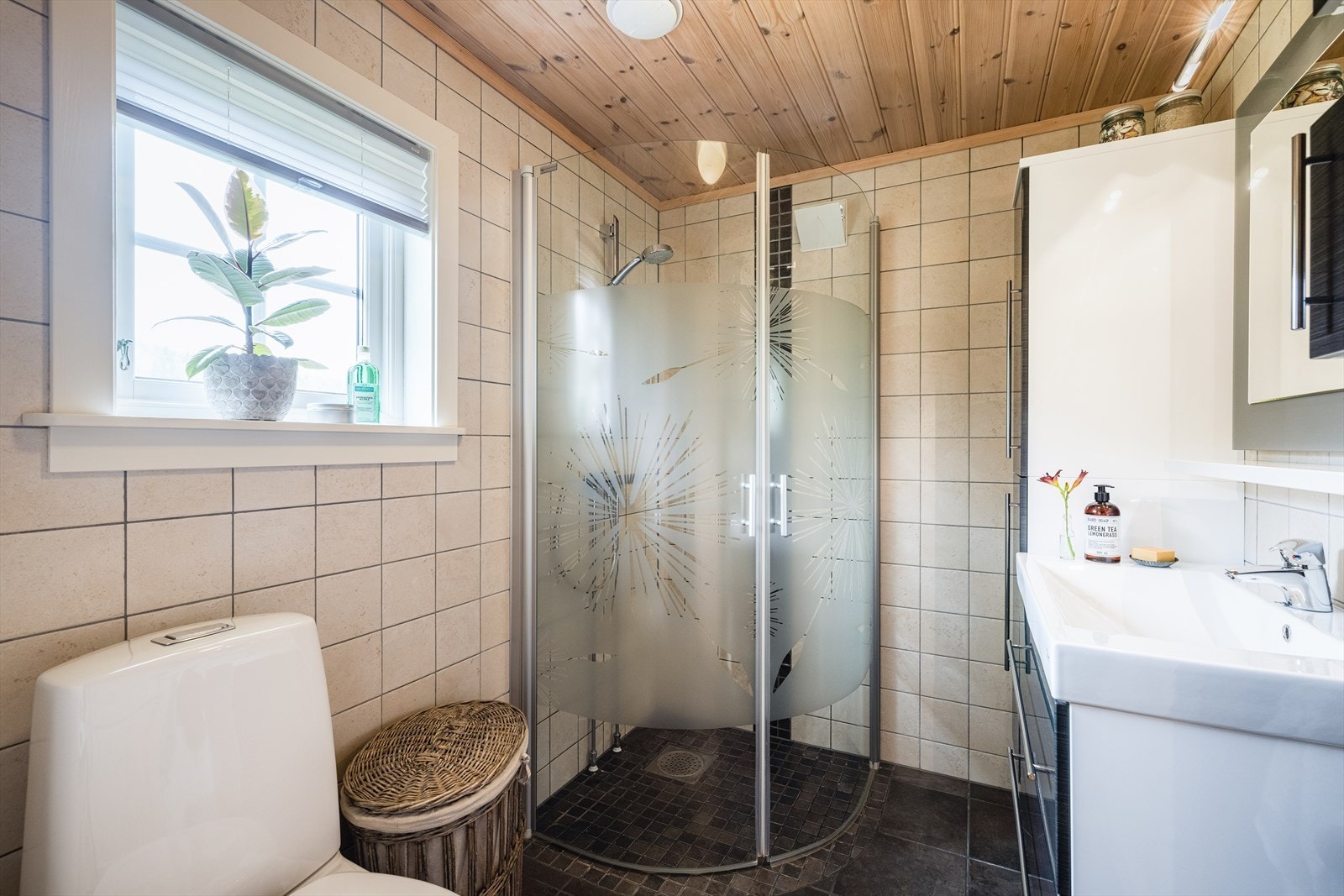 Badet er pusset opp i 2011 og inneholder heldekkende servant med underskap, overskap og speil med lys over. Videre inneholder badet gulvmontert toalett, dusjhjørne og et veggmontert høyskap. Galleribilde