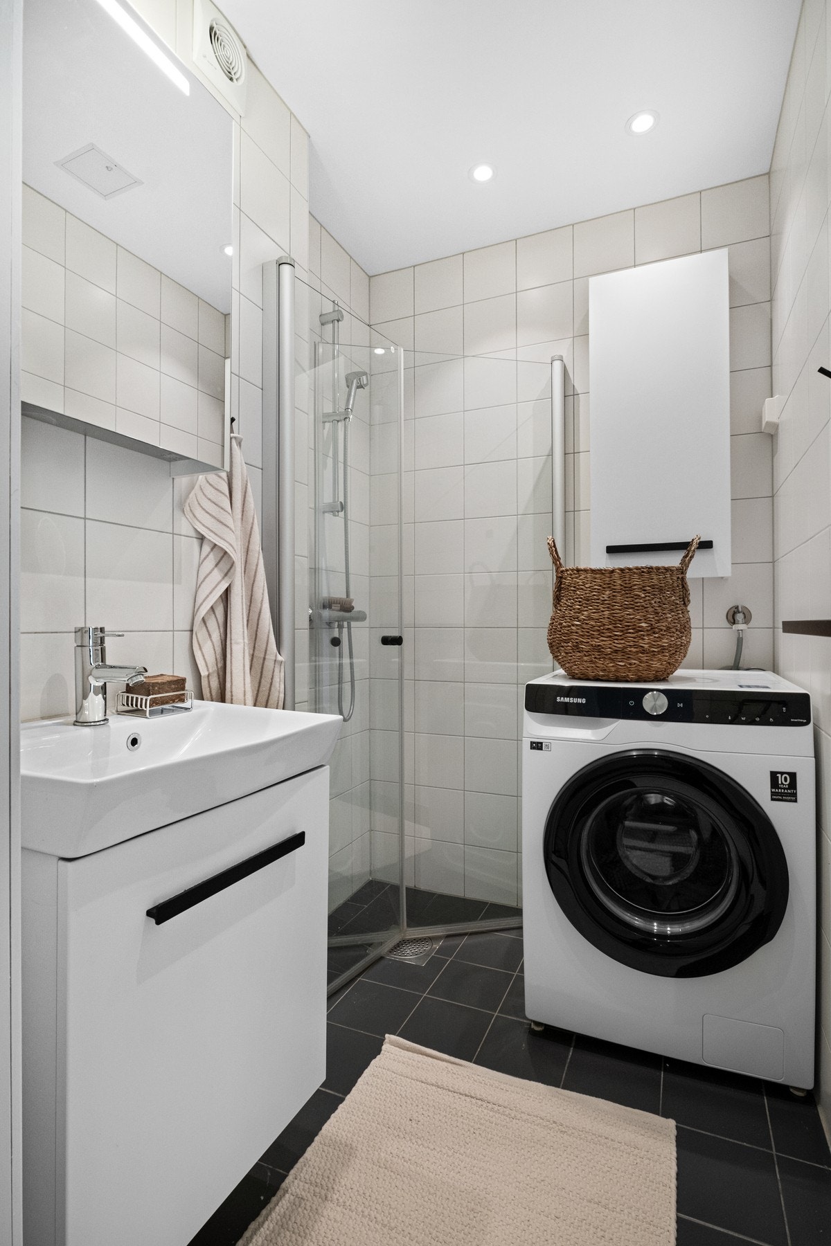 Badet er innredet med baderomsmøbel med servant, speilskap, dusj og opplegg for vaskemaskin. Galleribilde