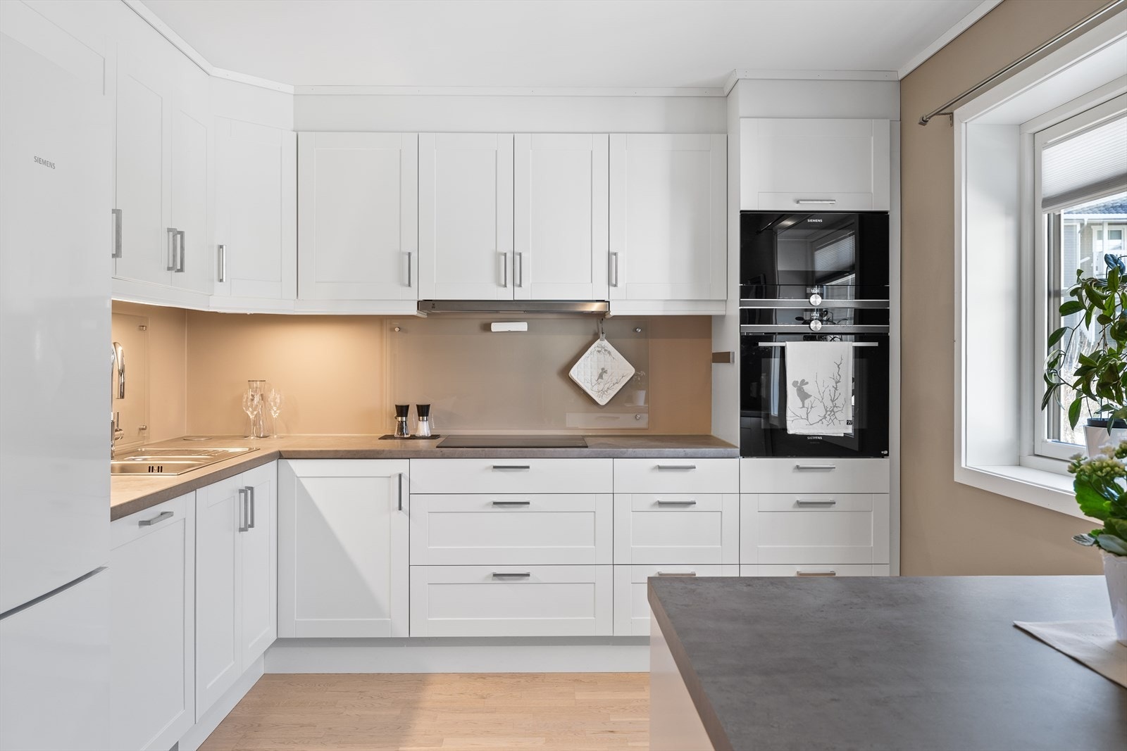 Stilrent kjøkken som har innredning med glatte fronter og benkeplate i høytrykkslaminat med nedfelt oppvaskkum. Galleribilde