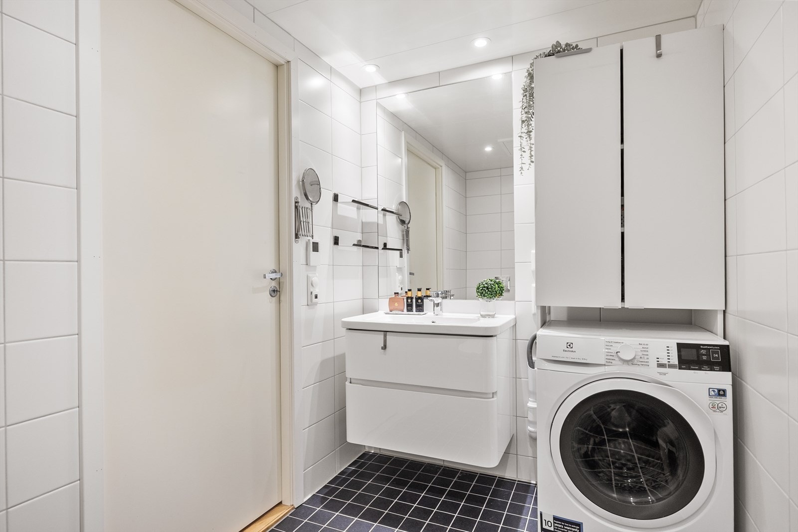 Ellers er det servant med skuffinnredning, speil, vegghengt skap og opplegg for vaskemaskin. Galleribilde