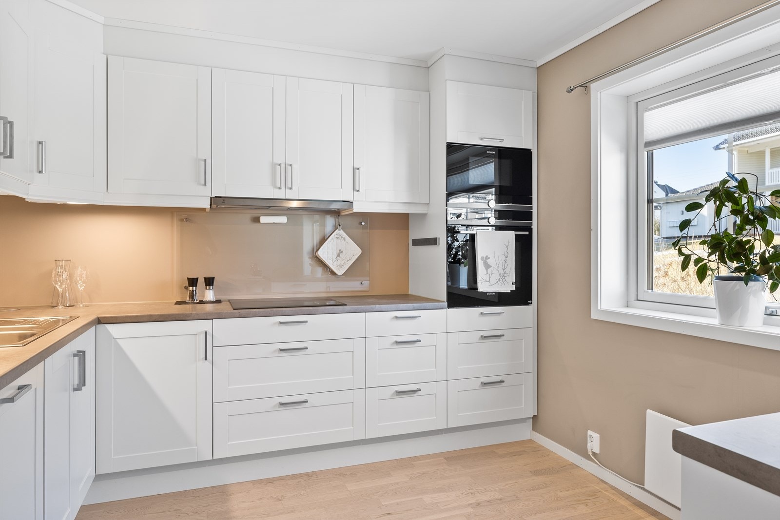 Den praktiske L-formen mellom stue, spisestue og kjøkken gjør rommet enkelt å møblere og skaper en naturlig flyt i boligen. Galleribilde