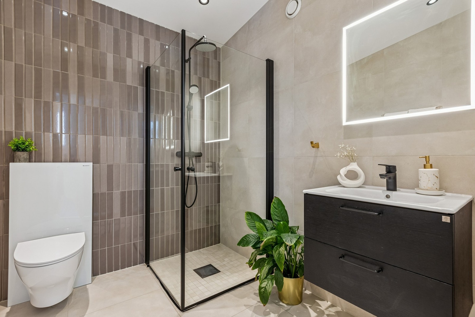 Badet er utstyrt med vegghengt toalett, dusjhjørne i glass og servantinnredning med speil. Galleribilde