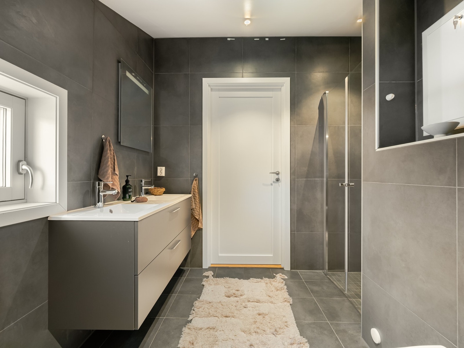 Det er innredet med vegghengt toalett, servantskap med oppbevaring og speil på vegg. Galleribilde