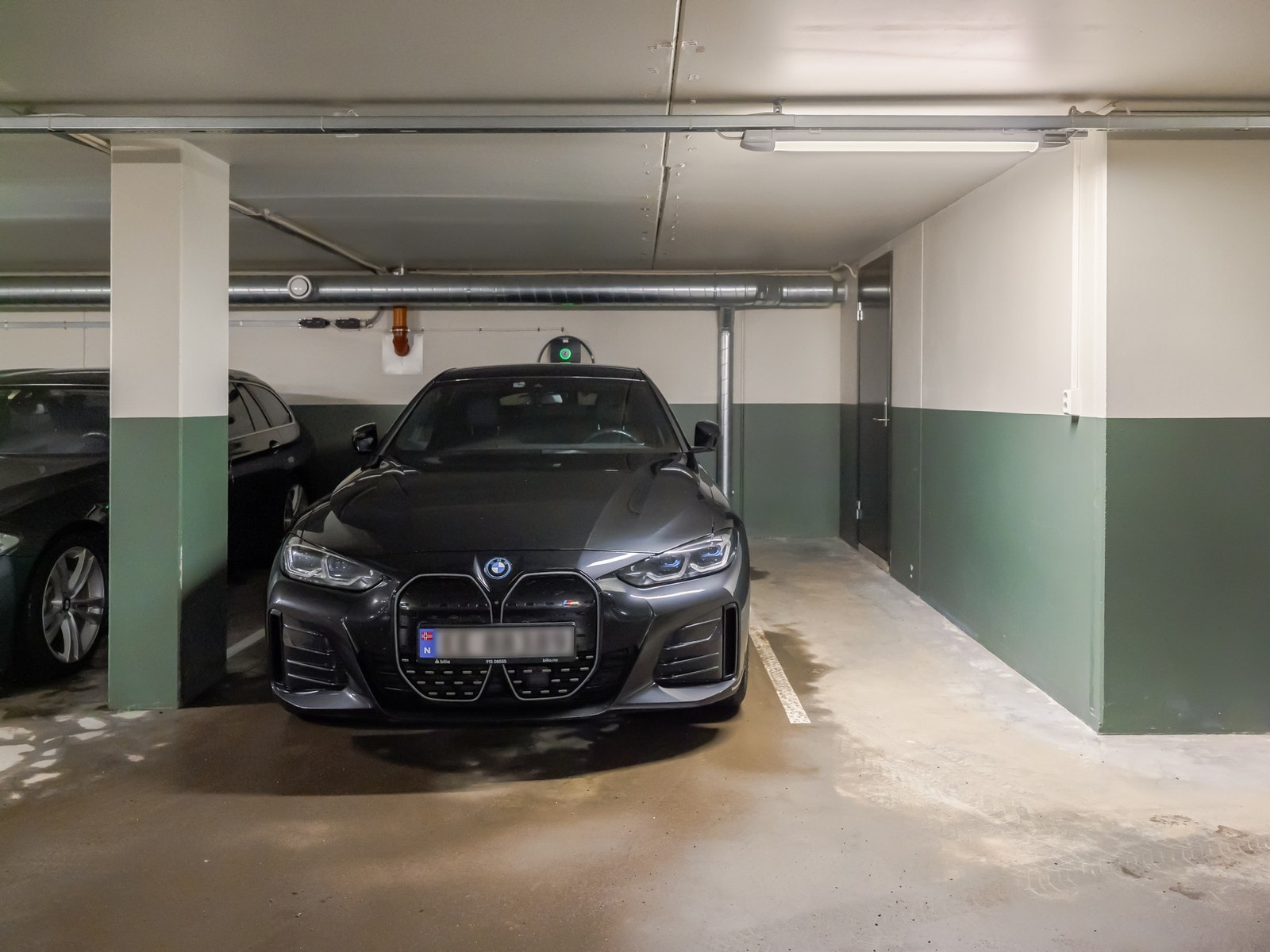 Garasjeplassen har en gunstig plassering med en solid stolpe som skiller den fra naboplassen. Døren til høyre i bakkant går inn til boligens fyrrom på ca. 12 kvm som disponeres sammen med én annen nabo. Galleribilde