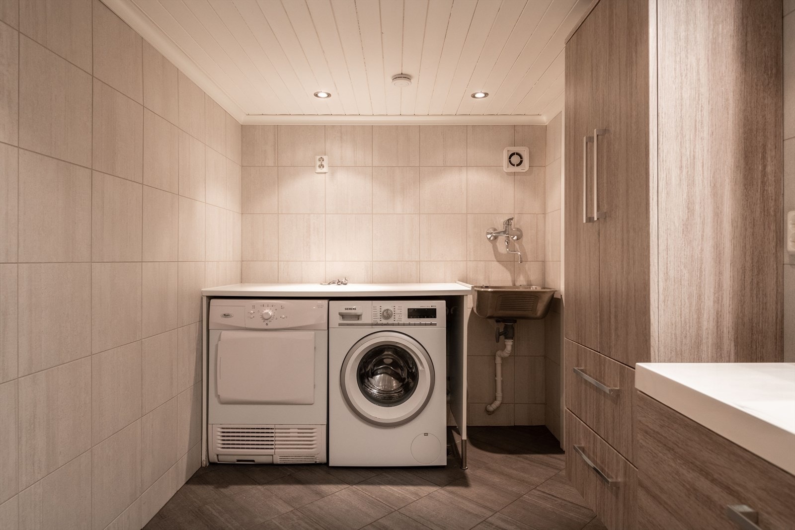 På badet i kjelleren er det etablert et eget område for vaskemaskin, tørketrommel og en egen utslagsvask. Galleribilde