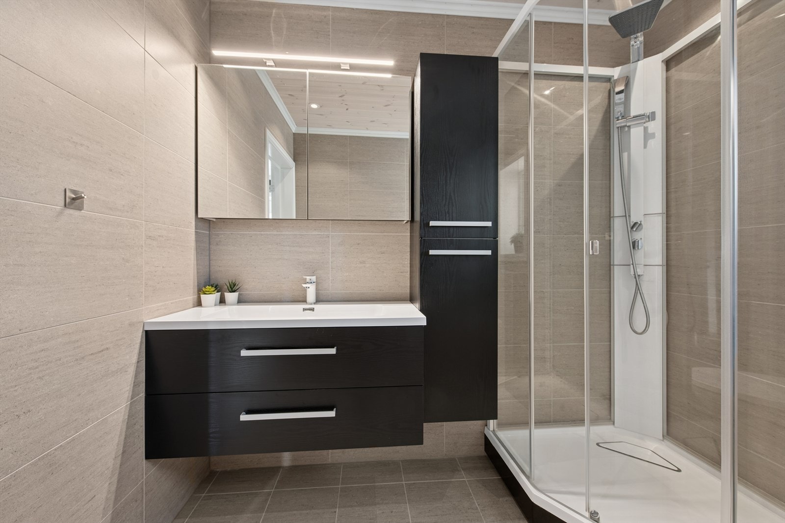 Baderommet er behagelig innredet med moderne fliser på gulv og vegg og med downlights i taket. Galleribilde