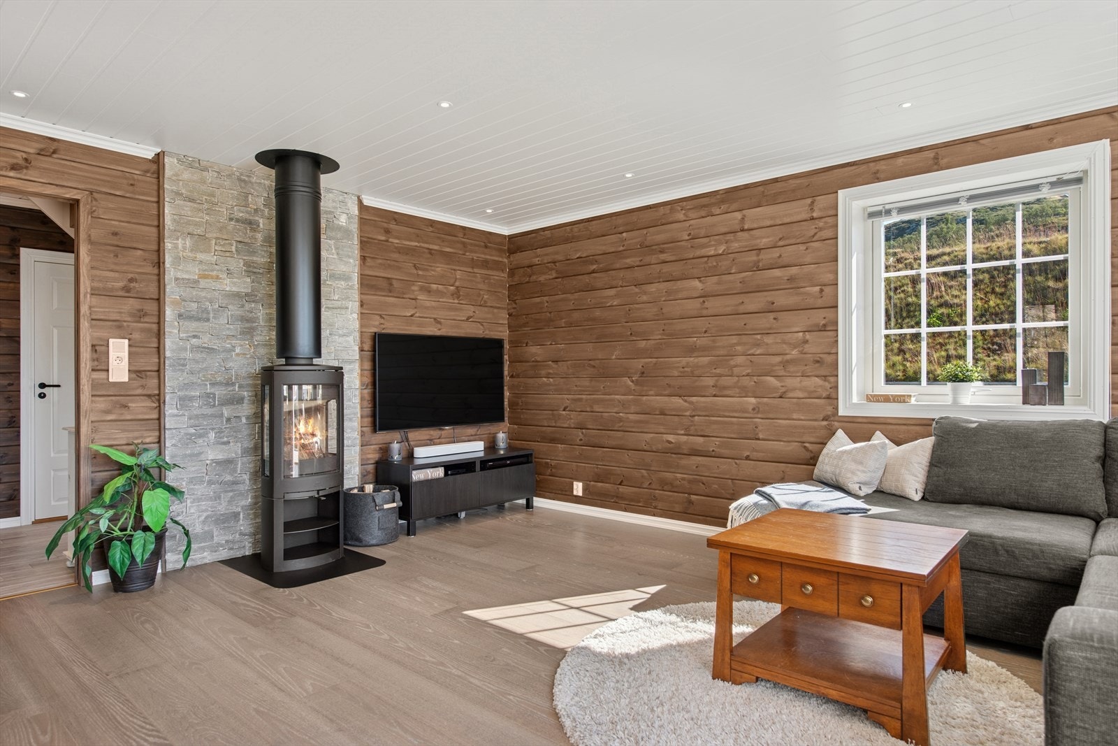 Stuen har trepanel på veggene og flott skiferdstein bak peisovnen. Galleribilde
