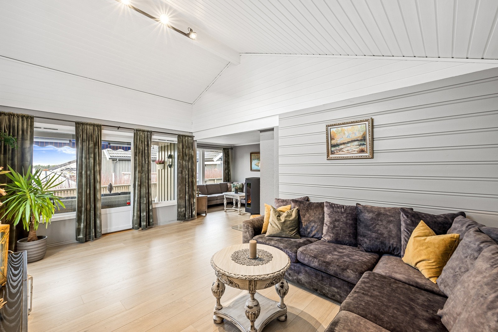 Den ene stuen har åpen himling og store vindusflater som slipper inn rikelig med naturlig lys, noe som gir en luftig og behagelig romfølelse. Galleribilde