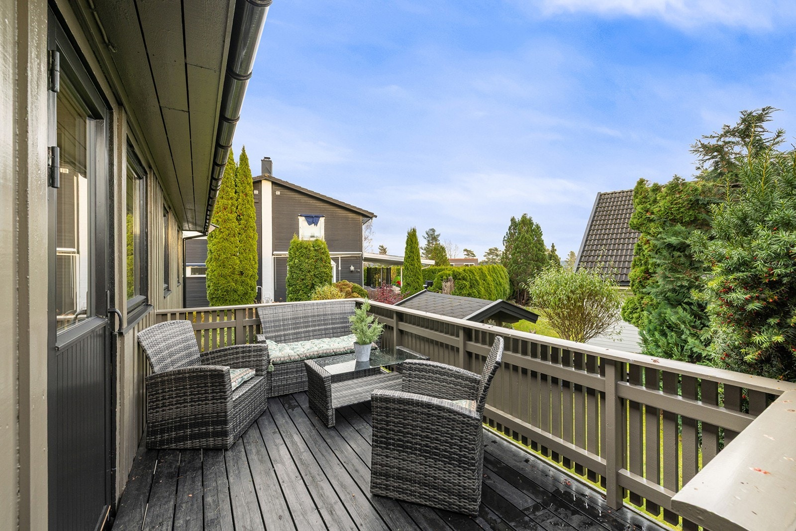 Terrassen utenfor kjøkkenet ligger skjermet og vender mot hagen, omgitt av grønne busker og trær som gir en hyggelig atmosfære og privatliv. Galleribilde