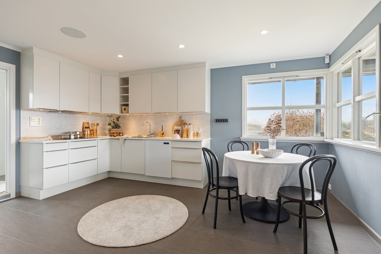 Lyst kjøkken med glatte fronter og integrerte høyttalere i tak. Galleribilde