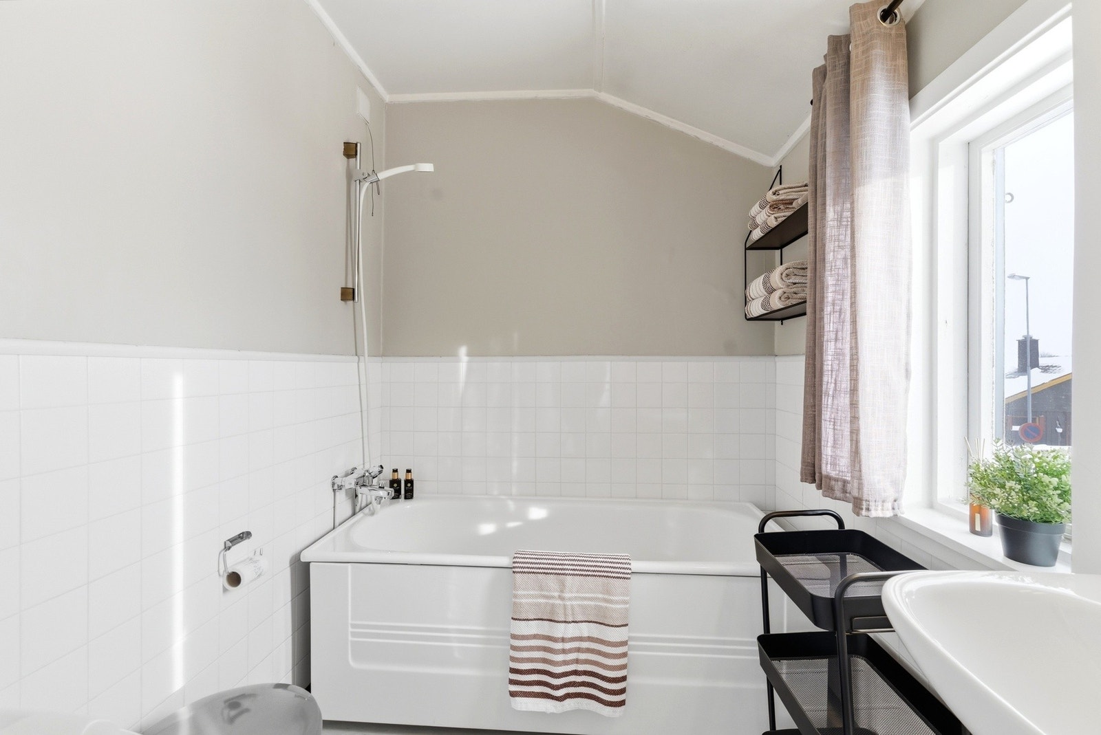 Bad innredet med badekar, gulvmontert toalett og servant montert på vegg. Galleribilde