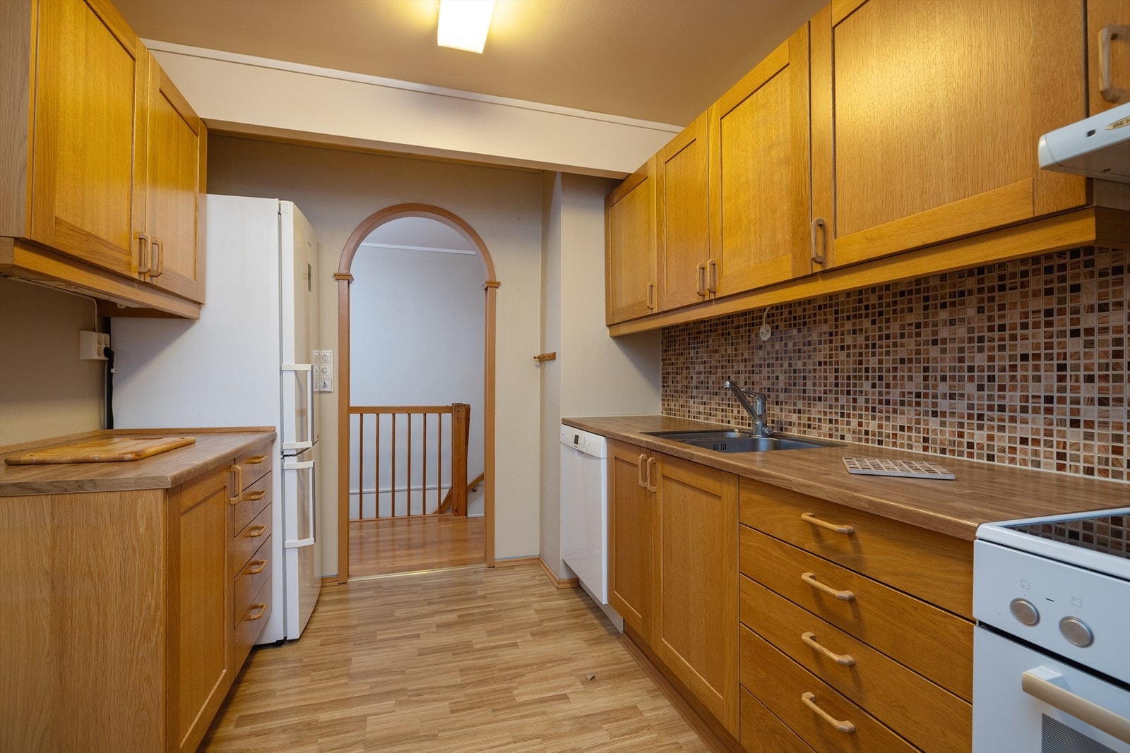 Kjøkkeninnredning med glatte fronter, laminat benkeplate og flislagt bakvegg. Galleribilde