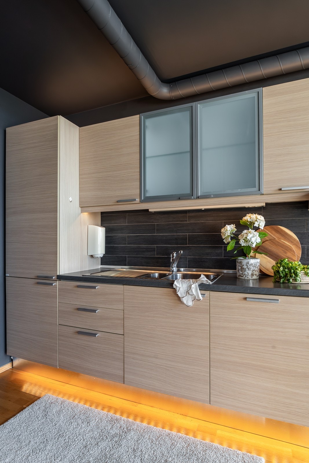 Detaljer i krom og belysning under kjøkkeninnredningen bidrar til et moderne og stilrent preg. Galleribilde