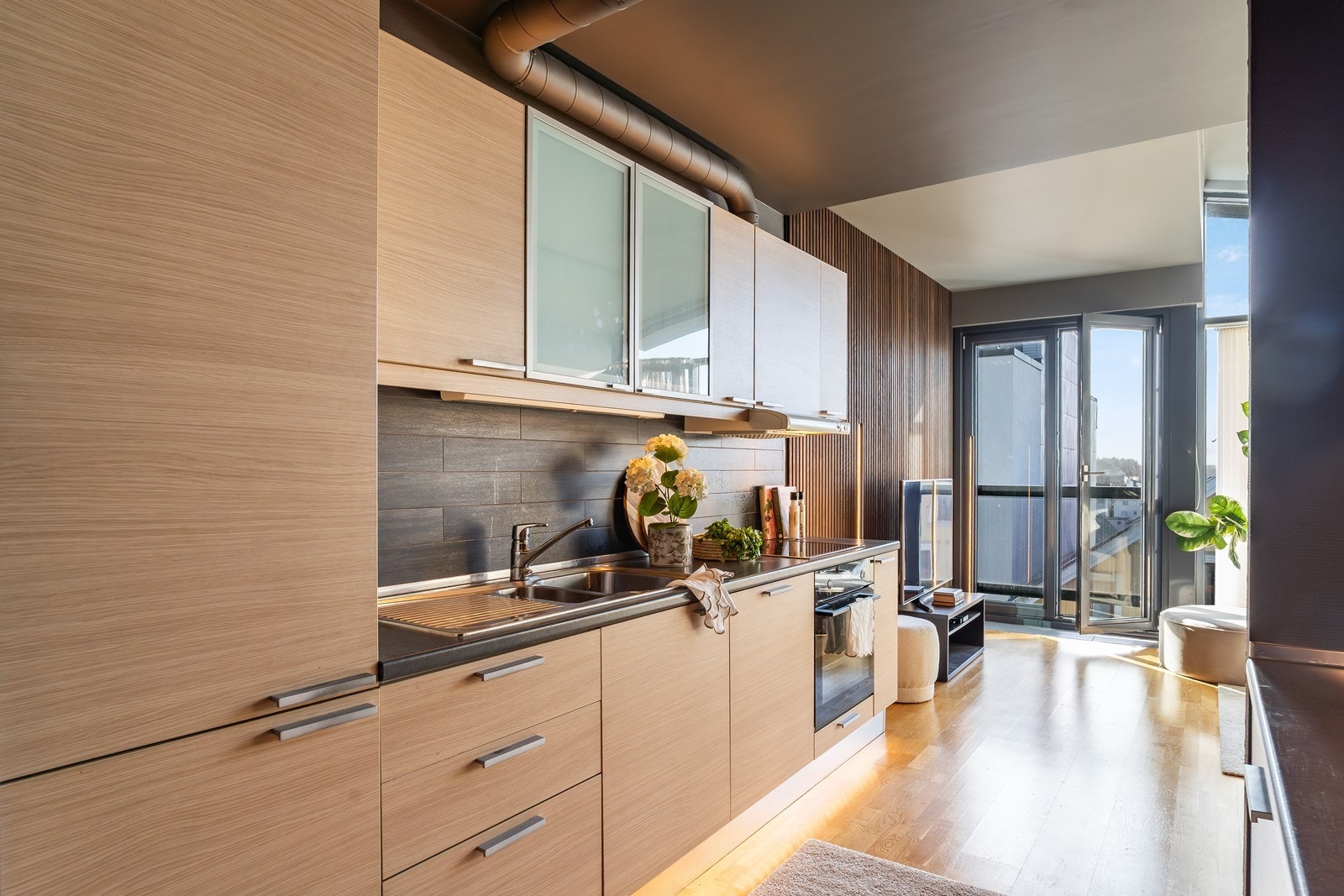 Kjøkkenet har integrerte hvitevarer og stilige, praktiske fliser over kjøkkenbenk. Galleribilde