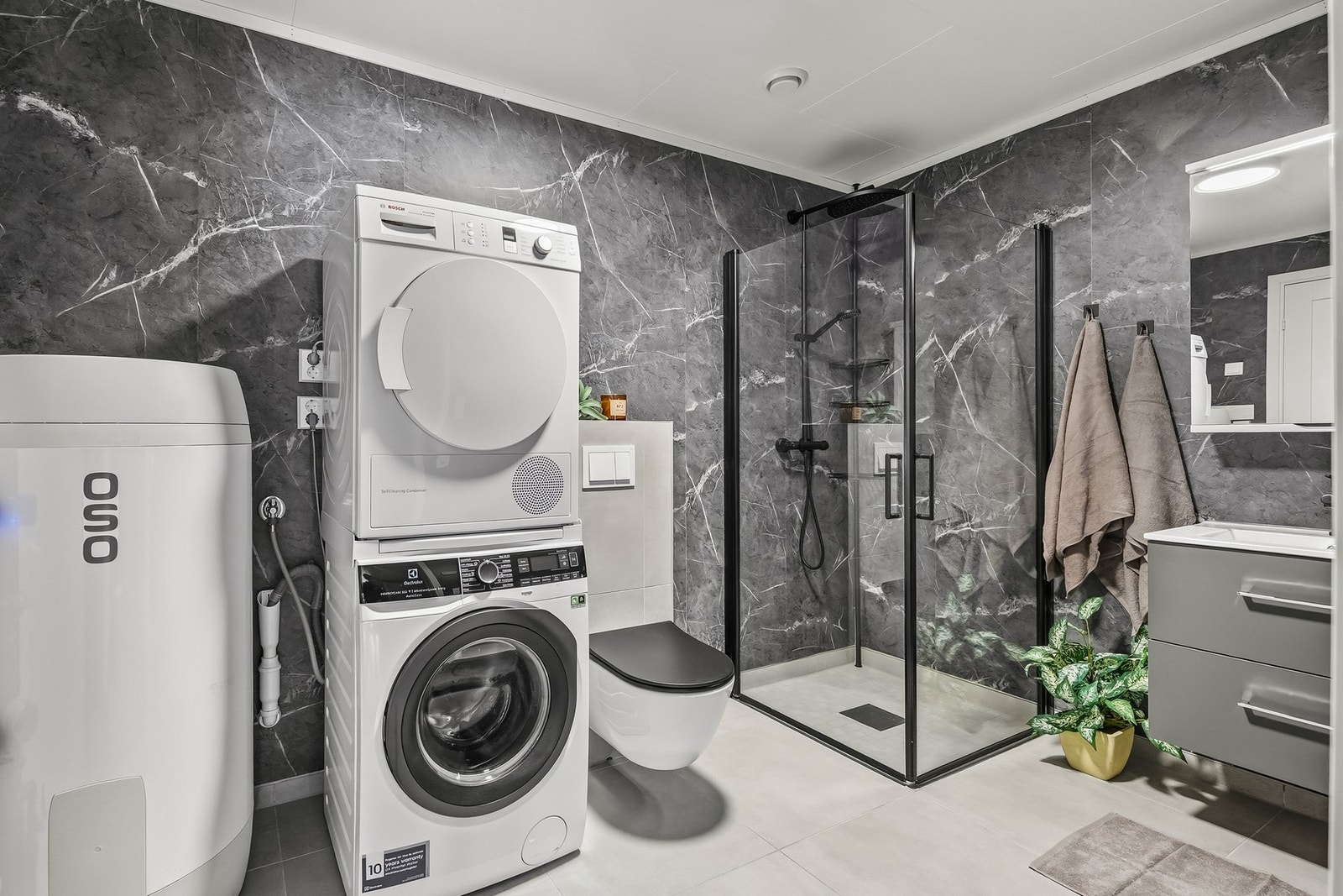 Bad u. etg. Vegghengt premium toalett, og 60 X 60 fliser. Dusjhjørne med glassvegger og baderomsinnredning med servant og høyskap. I tillegg er det opplegg for både vaskemaskin og tørketrommel. Galleribilde