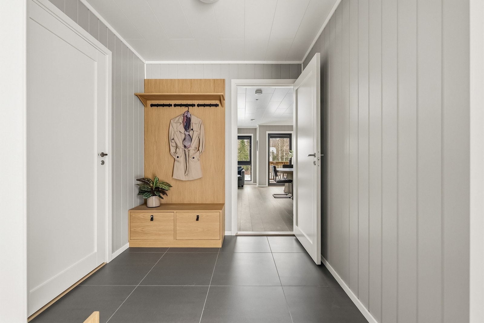 Gang med plassbygd gangmøbel i eik (lagd av lokal møbelsnekker). Inngang til garderobe til venstre i bildet. Entréen gir et ryddig og innbydende førsteinntrykk, og fungerer som et naturlig bindeledd videre inn i boligen. Galleribilde