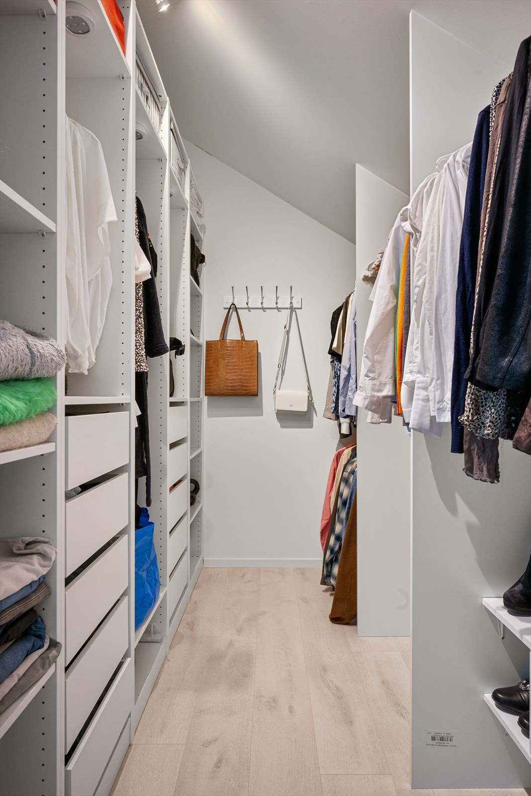 Walk in garderobe med mye plass for oppheng, skuffer og skap. Ekstra lys i skapene, med praktisk fjernkontrollstyring. Galleribilde