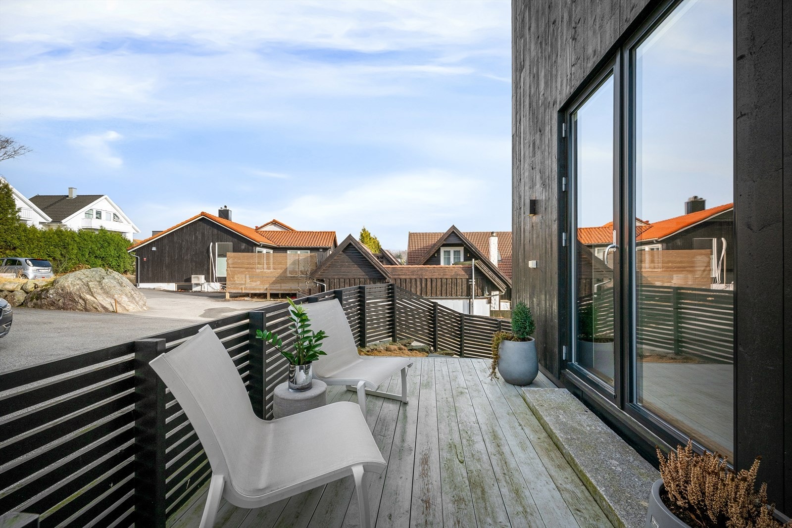 Perfekt terrasse for morgenkaffen. Stilmessig rent, fin bruk av steintrinn mot tredekke. Sorte karmer på vinduer og dører. Galleribilde