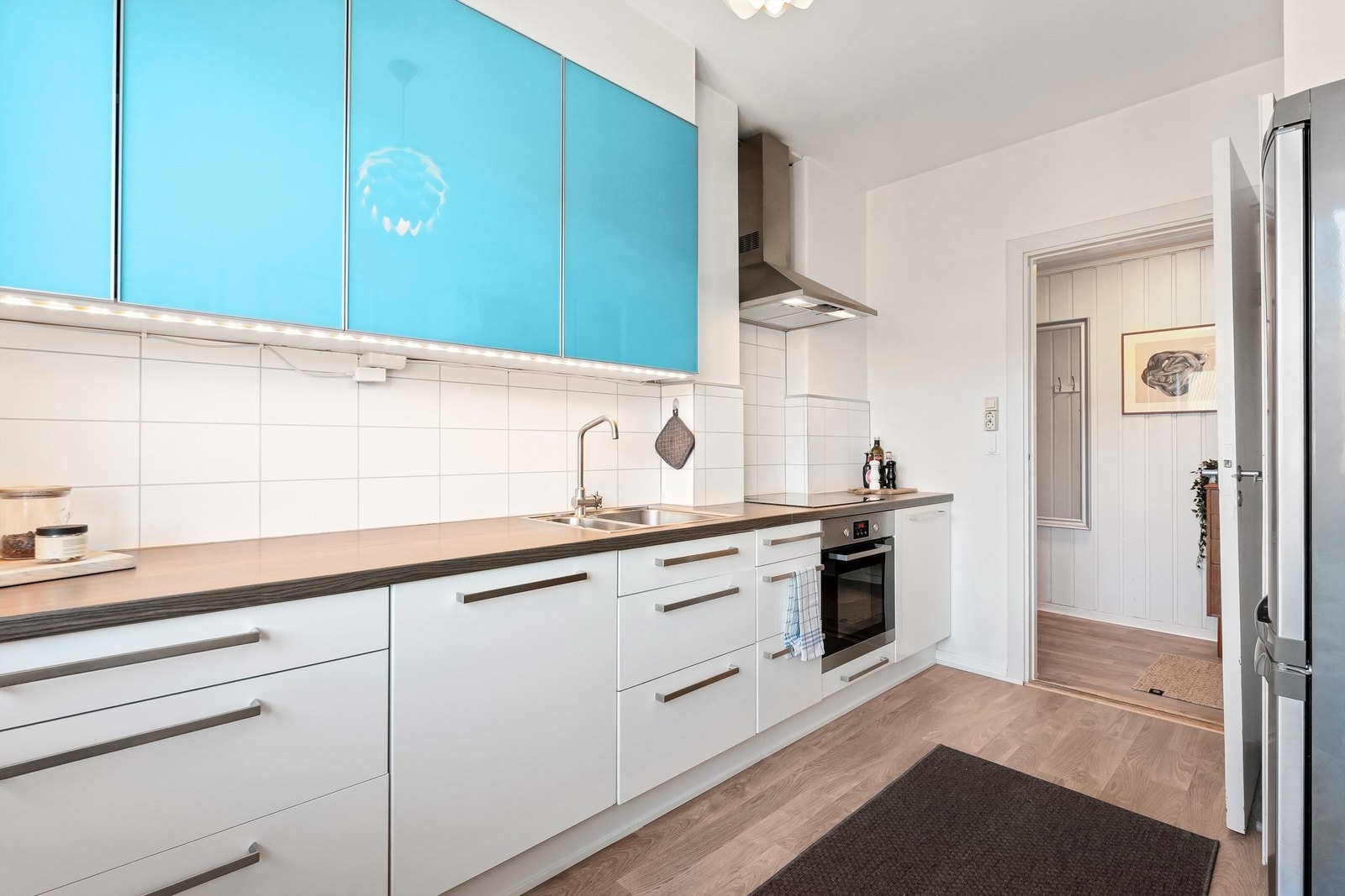 Kjøkkenet er utstyrt med integrerte hvitevarer, inkludert stekeovn, platetopp og oppvaskmaskin, samt et frittstående kjøleskap med fryser Galleribilde