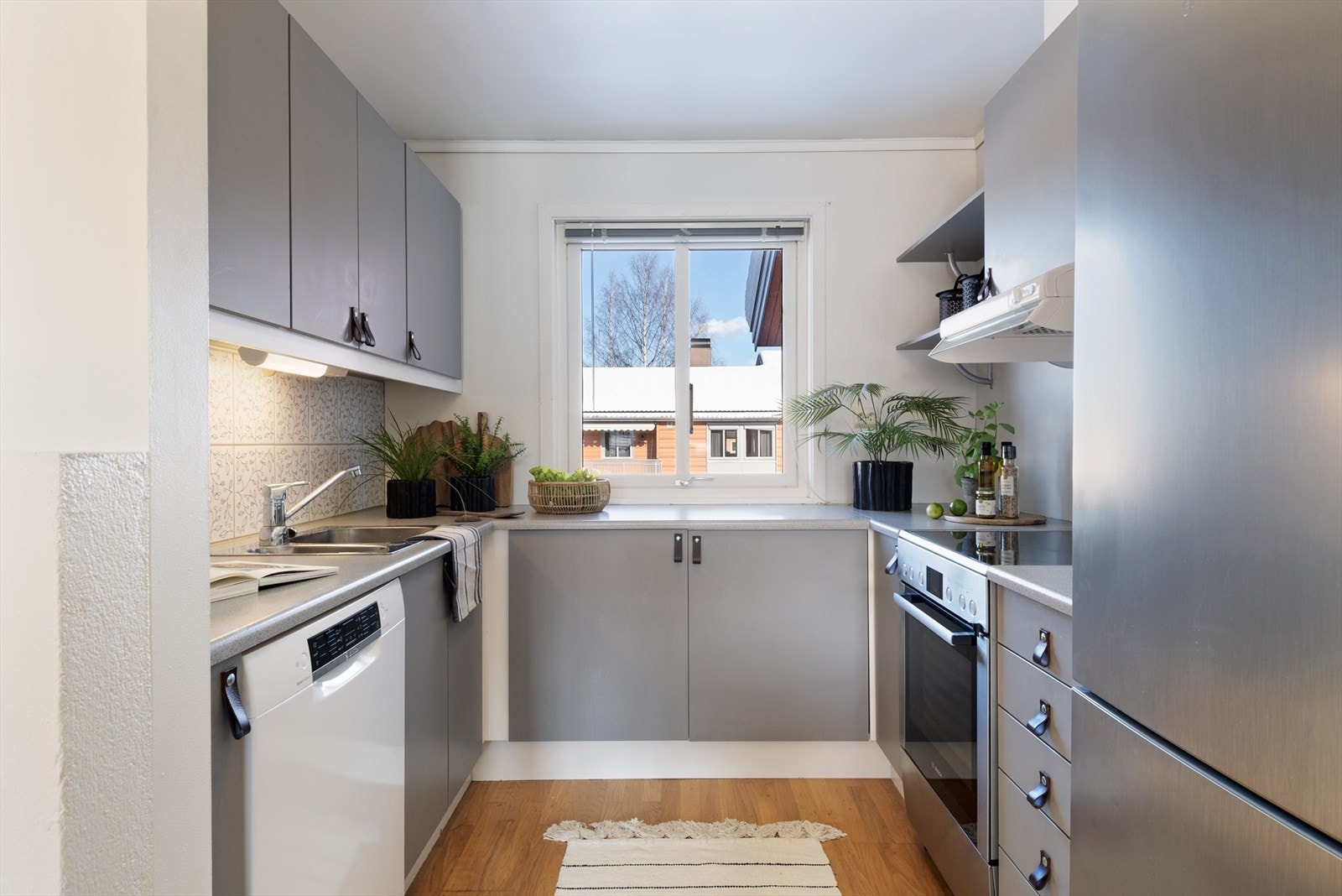 Grå kjøkkenfronter og benkeplate i laminat gir et funksjonelt arbeidsområde. Galleribilde