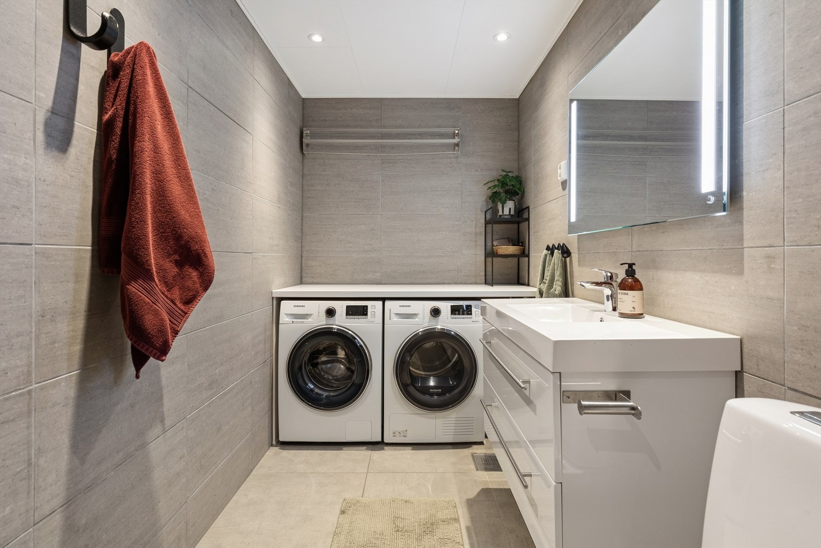 Delikat og romslig bad med moderne innredning. Opplegg for vaskemaskin og tørketrommel gir en praktisk løsning. Galleribilde