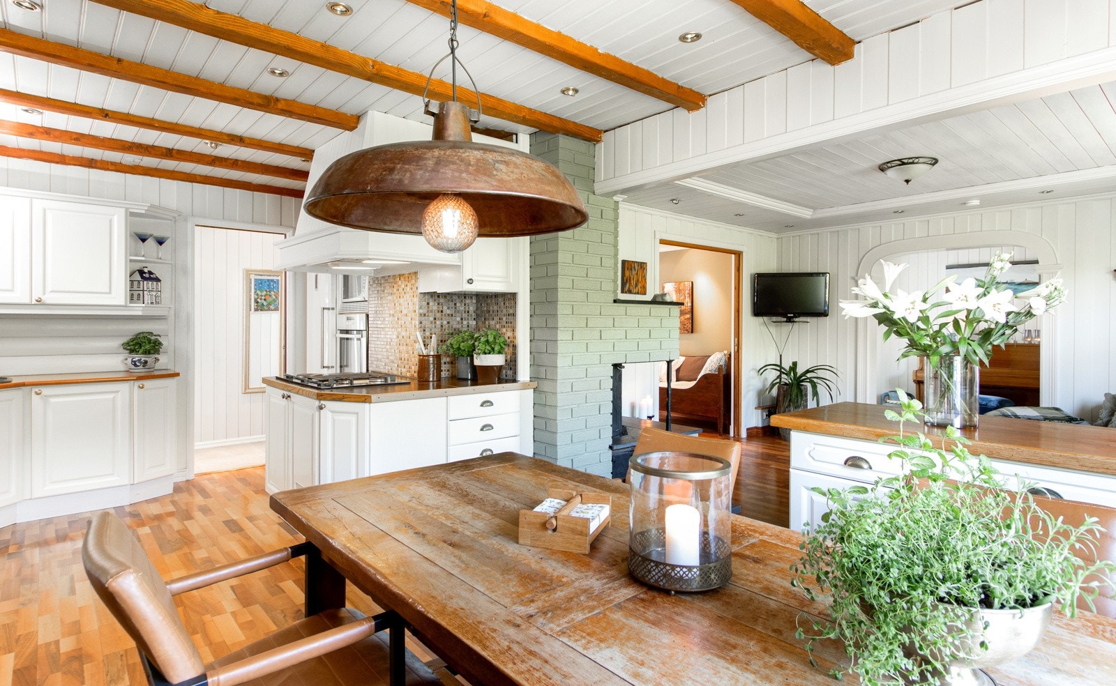 Kjøkkenet gir et varmt og trivelig inntrykk med laminatgulv, malt veggpanel, samt downlights og pyntebjelker i himling. Galleribilde