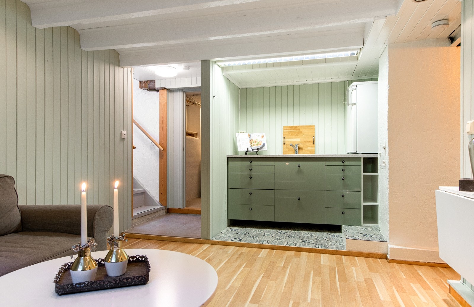 Det er etablert en åpen kjøkkenløsning i enden av kjellerstuen. Rommet har ingen ventilator eller kokemuligheter, men det er servant og kjøleskap på benken. Galleribilde