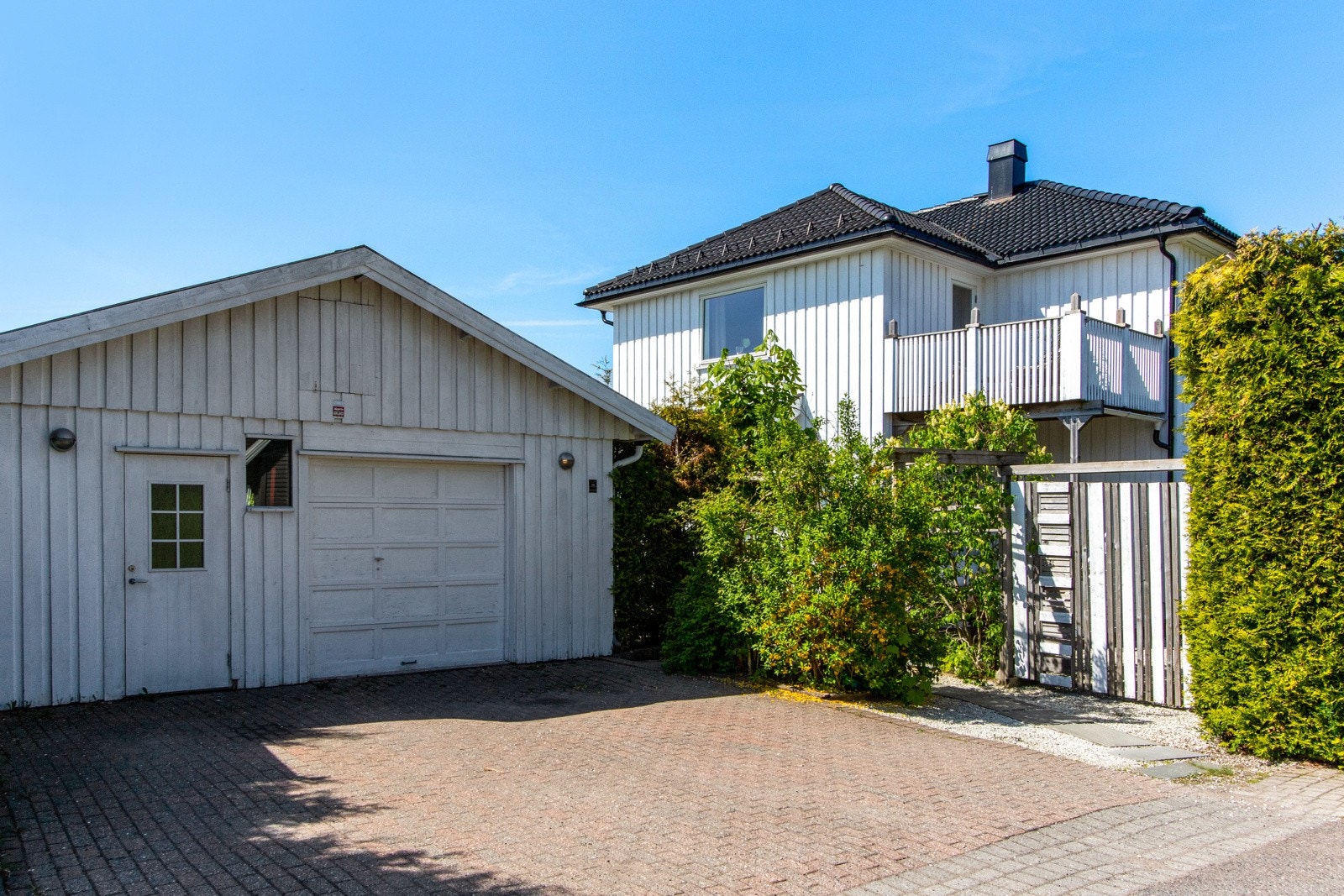 Det er parkering i frittstående garasje med leddport i tre. Garasjen har dør ved siden av garasjeporten og en tofløyet dør ut til uteplass på baksiden. Galleribilde