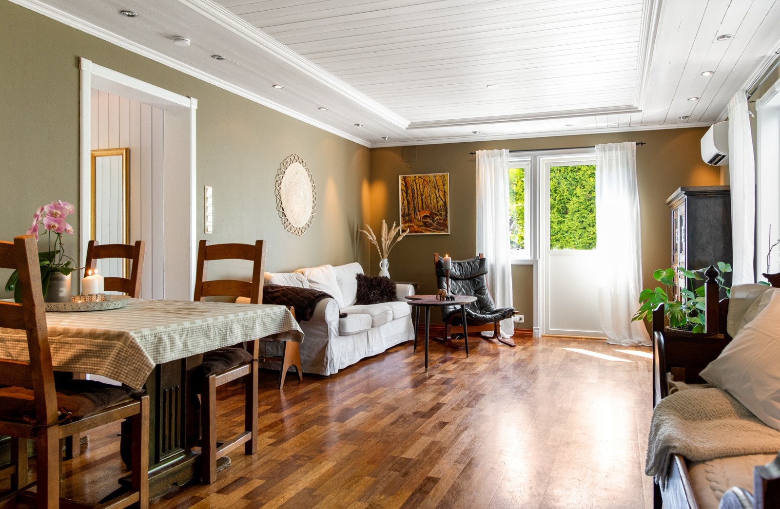 Stuene har parkettgulv, gode vindusflater, veggflater malt i tidsmessige fargetoner og downlights langs ytterkant av himling. Galleribilde