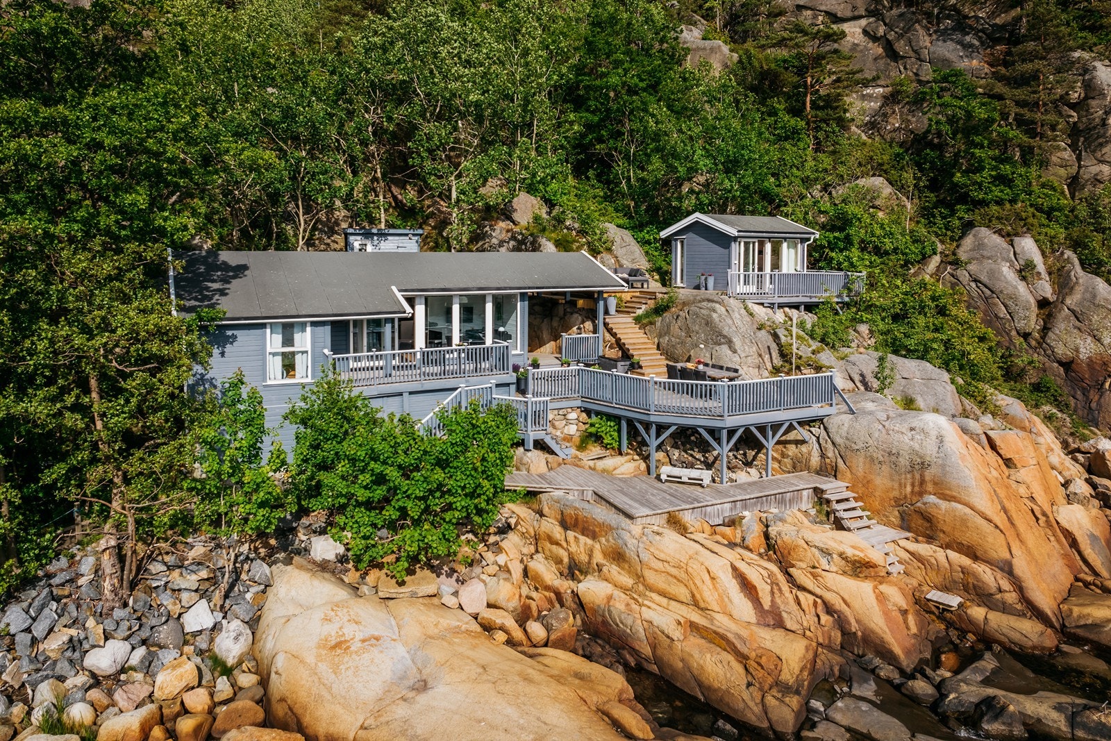 Denne hytta sklir godt inn i terrenget og med sin blågrå farge tar den opp sjøen på utsiden. Galleribilde