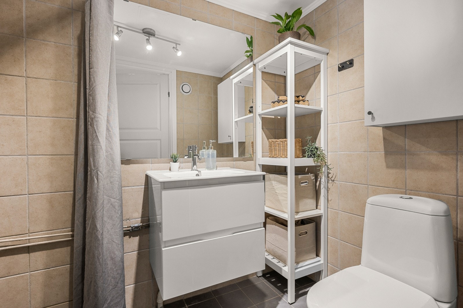 Badet er fra 2010 og har flislagte overflater, lagringsplass i skuffeinnredning og skap på vegg. Galleribilde