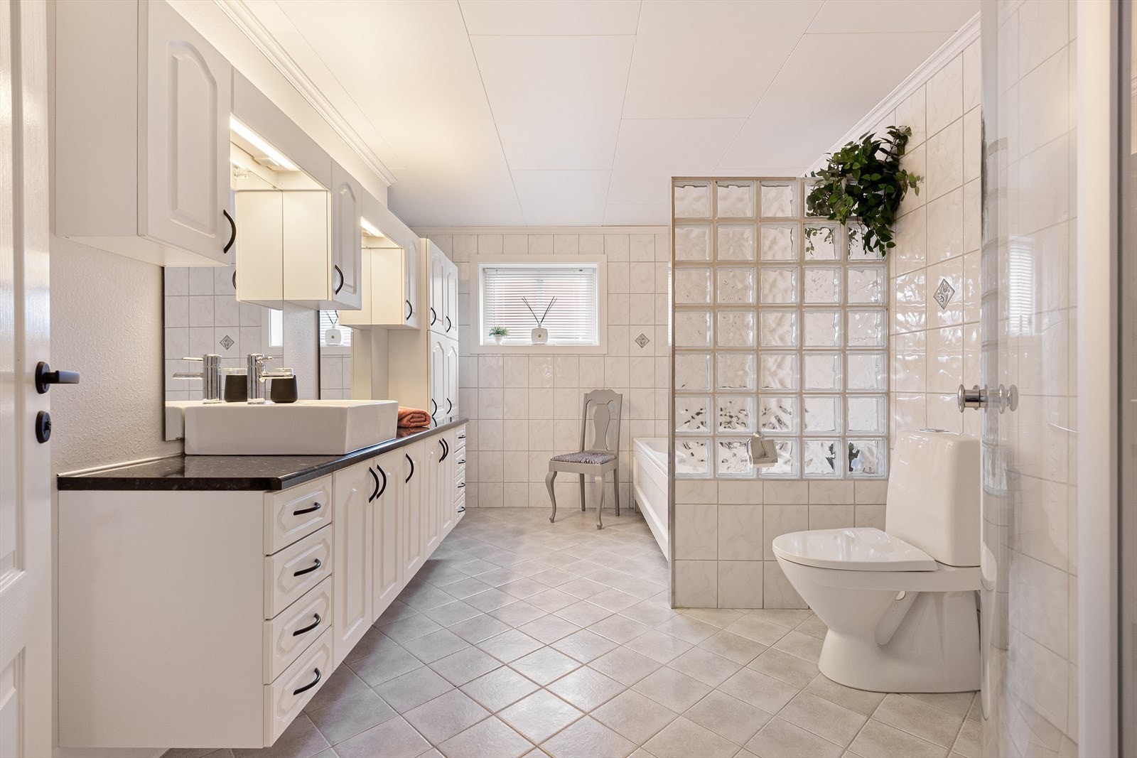 Bad i hovedetasje med wc, badekar, servant og dusjsone med innskyvbare dusjvegger. Fliser på gulv og på tre av veggene. Galleribilde