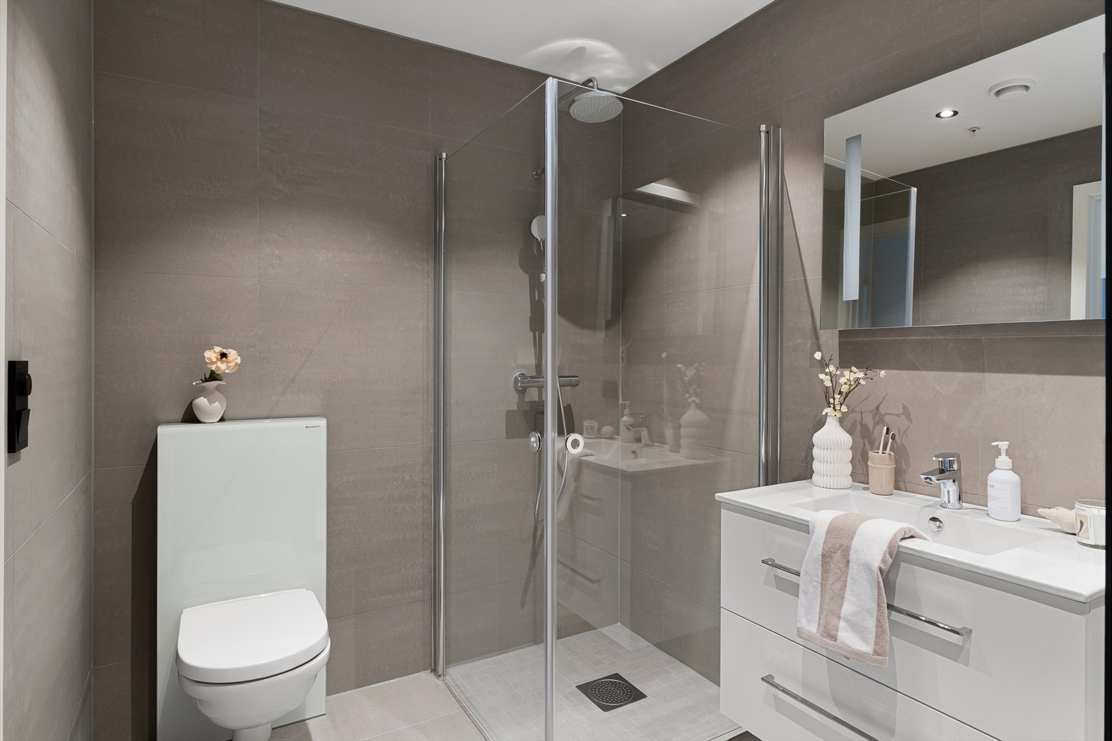 I direkte tilknytting til entré/gang har man tilgang til et flott helfliset bad med 60x60 fliser, vegghengt wc, dusjhjørne og varme i gulv for ekstra komfort. Galleribilde