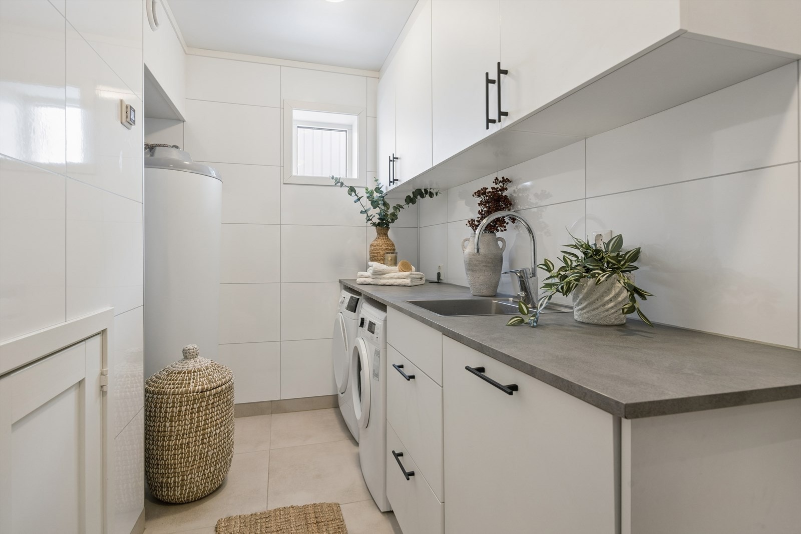 Separat vaskerom med flislagt gulv, god skapinnredning og opplegg for vaskemaskin. Galleribilde