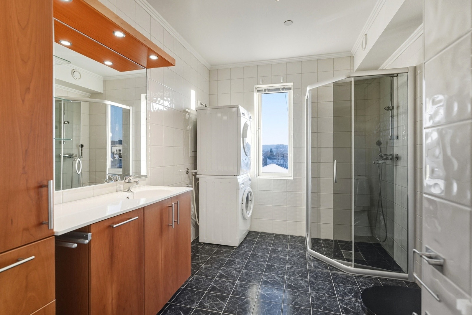 Det er innredning med nedfelt servant, toalett, dusjvegger/hjørne og opplegg for vaskemaskin. Galleribilde