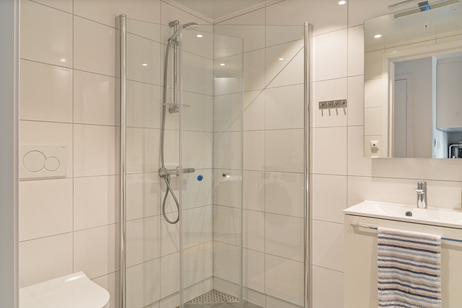 Badet er utstyrt med baderomsinnredning med nedfelt servant, vegghengt toalett dusj og opplegg for vaskemaskin Galleribilde