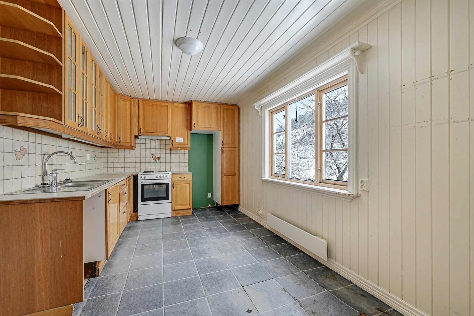 Kjøkkenet har innredning med profilerte fronter og laminat benkeplate, med potensial for modernisering. Galleribilde