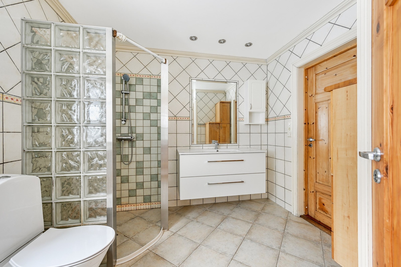 Innredningen består av heldekkende servant, gulvmontert toalett og dusjvegger i glassbyggerstein. Galleribilde