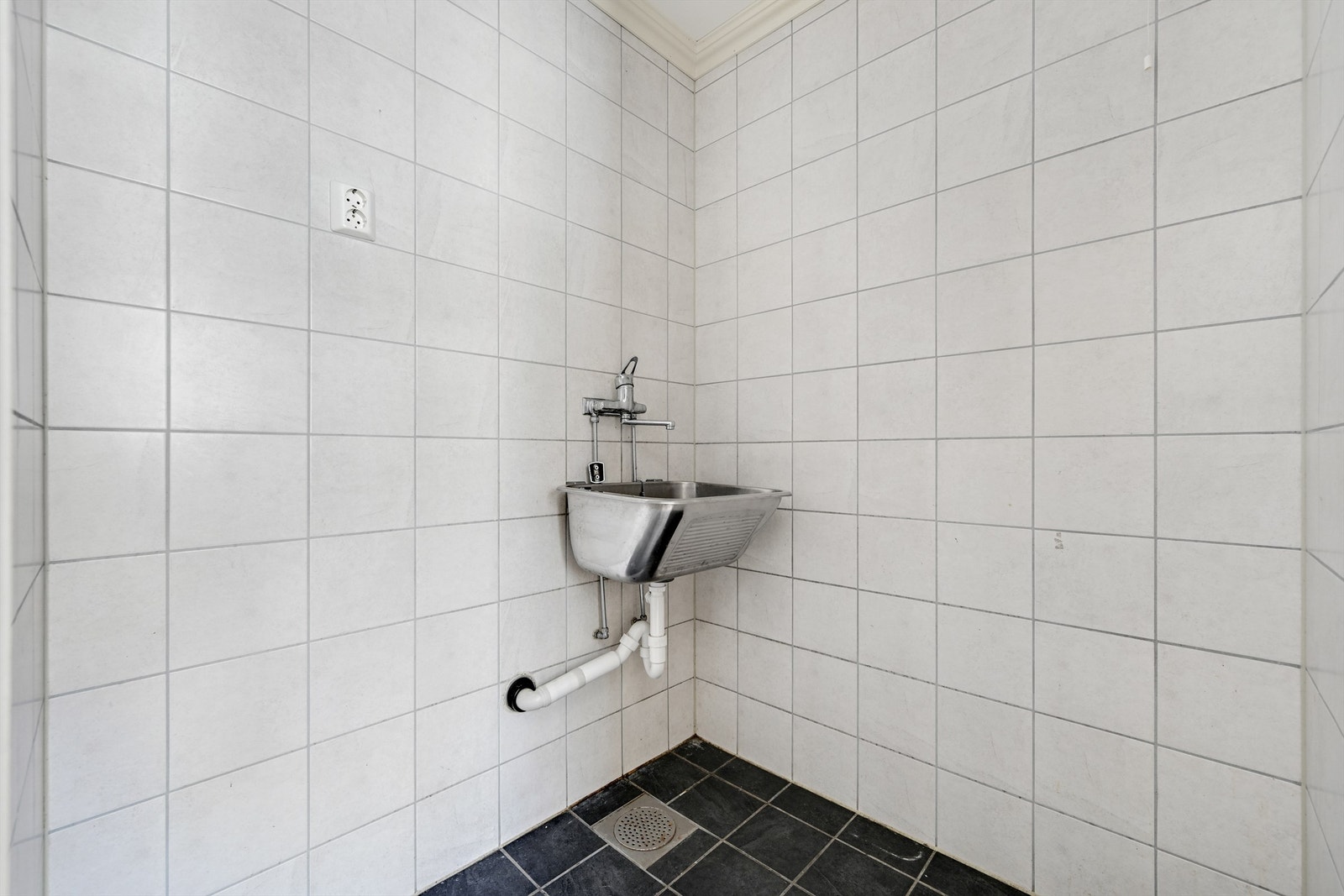 Praktisk vaskerom i første etasje med fliser på gulv, skyllekum og opplegg for vaskemaskin. Galleribilde