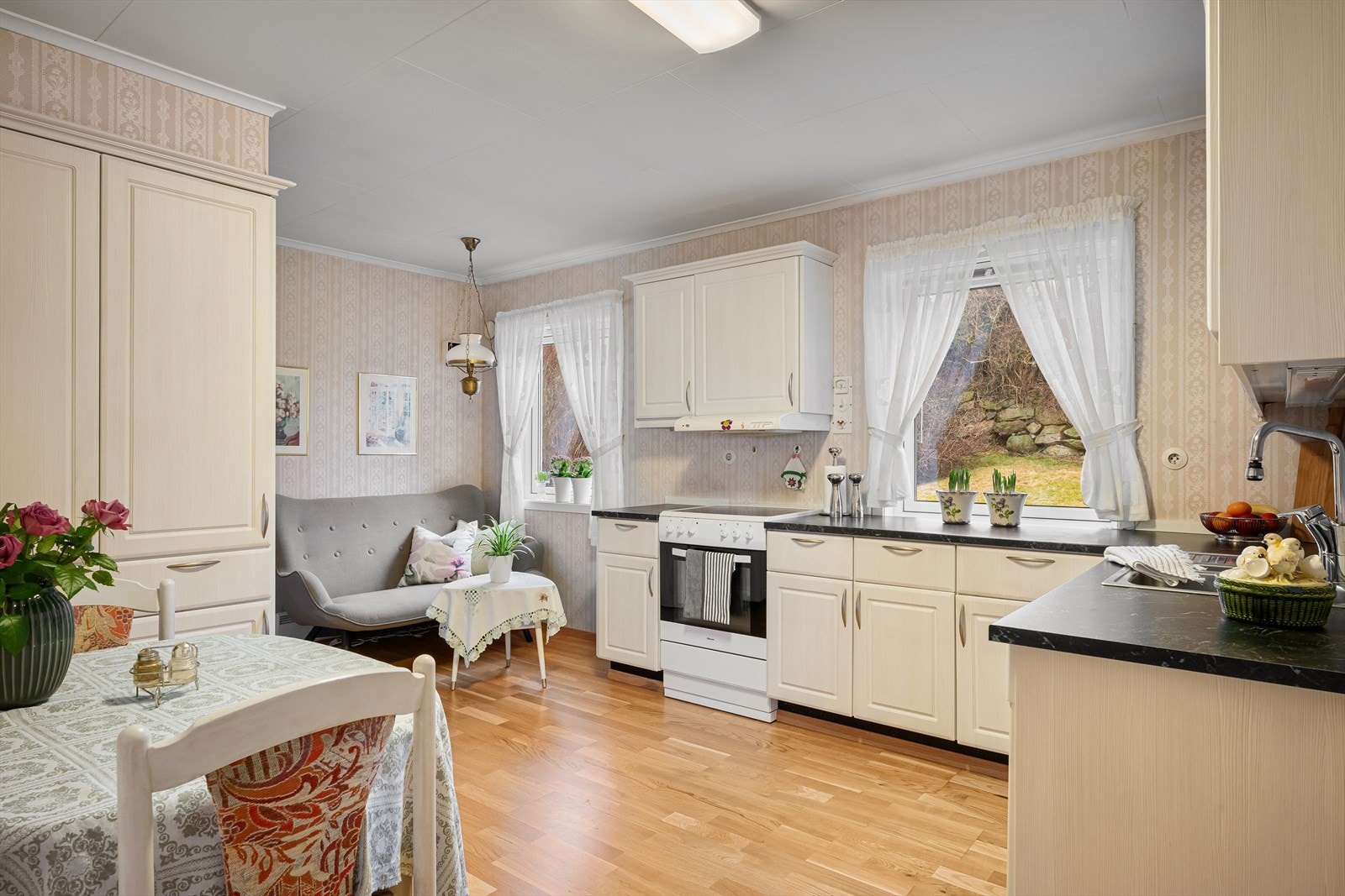 Et romslig kjøkken fornyet i ca. 2016 som innbyr til sosial samling med både lite spisebord og en lounge for avslapning. Rikelig med skapplass og arbeidsbenk. Fint utsyn til egen bakhage og mye naturlig lys. Galleribilde